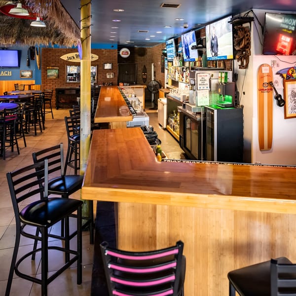 Interior of Beach Sports Grill & Bar, featuring a long wooden bar, high-top tables, and multiple TVs.