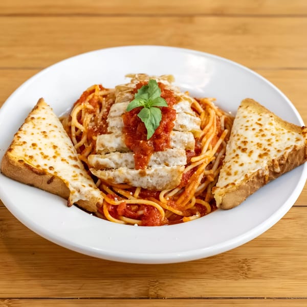 Spaghetti with chicken, marinara sauce, fresh basil, and two slices of cheesy garlic bread.